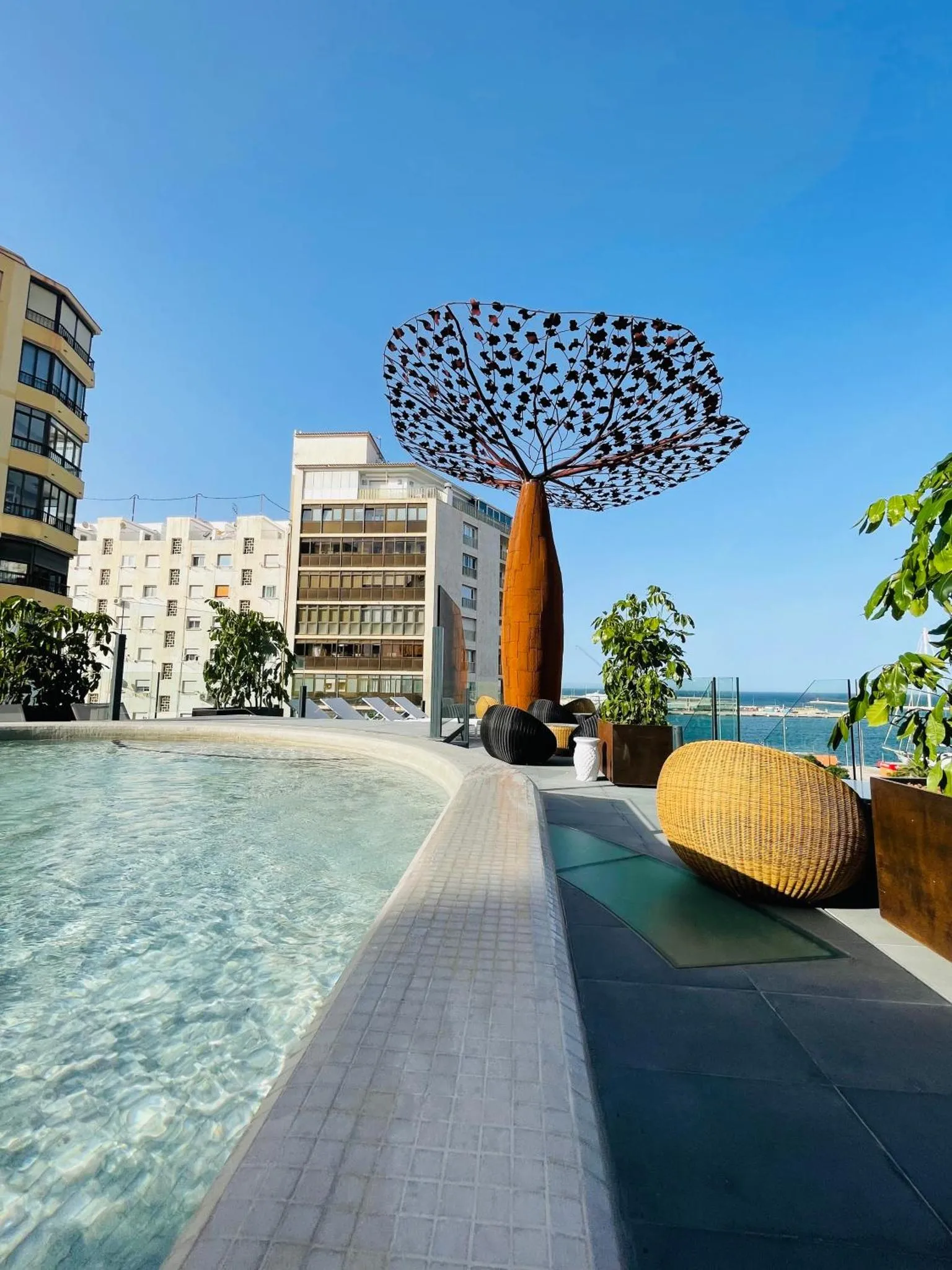 Piscine à débordement avec vue sur la mer et sculpture contemporaine.
