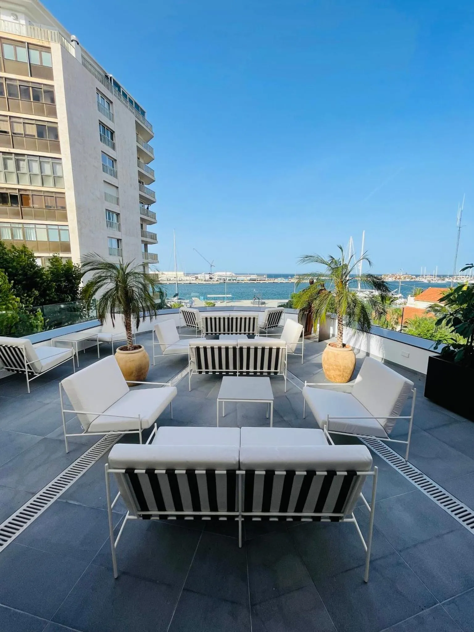 Terrasse aménagée avec des transats et des canapés blancs face à la mer.