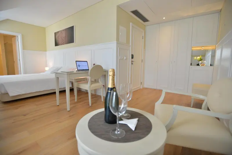 Une chambre lumineuse avec un bureau et une bouteille de champagne.