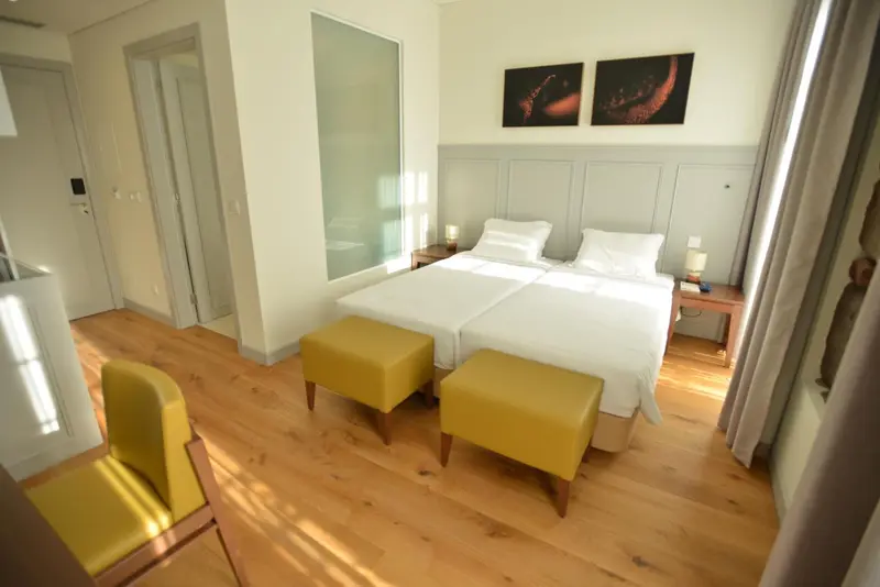 Une chambre lumineuse avec deux lits simples et un mobilier jaune.