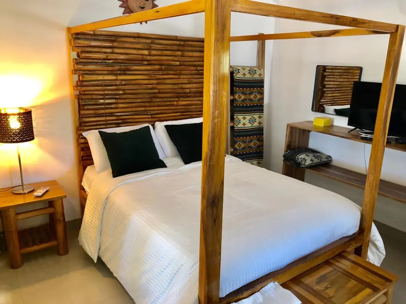 Une chambre avec un lit à baldaquin en bois et une décoration murale en bambou.