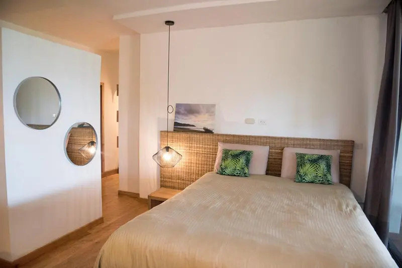 Une chambre lumineuse avec un grand lit et des coussins décoratifs.