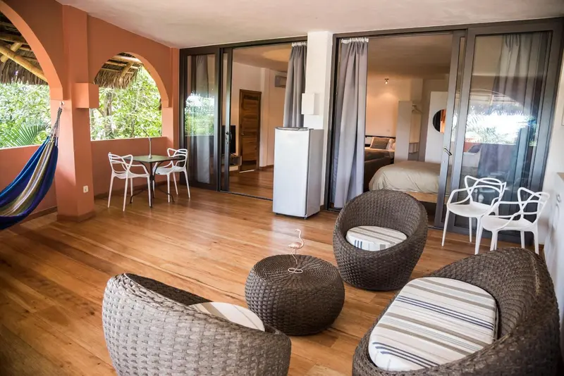 Espace de vie intérieur avec mobilier en rotin et accès à une terrasse.