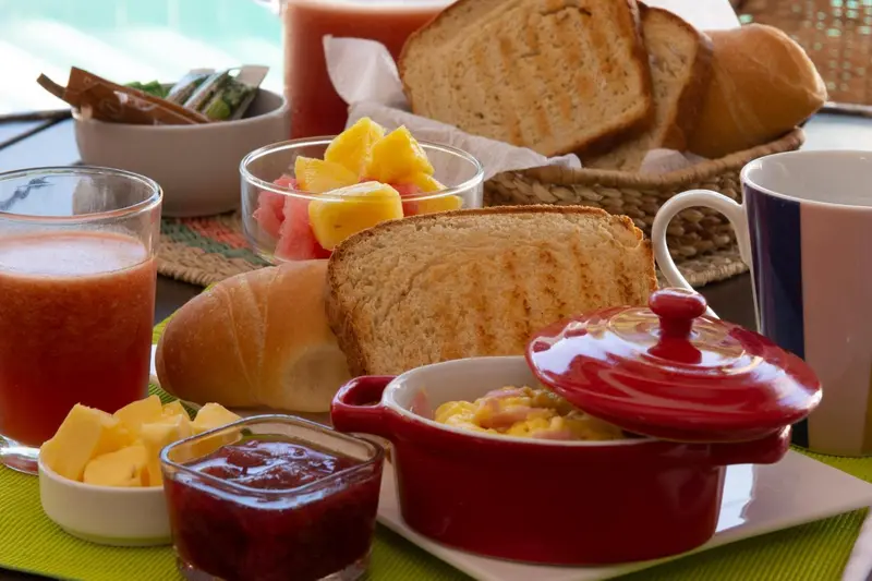 Une table est dressée avec des viennoiseries, des fruits frais et des confitures.