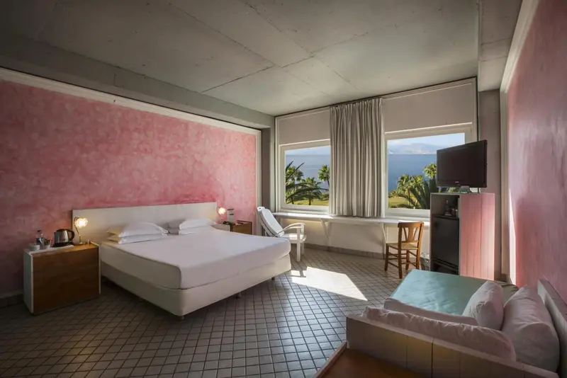 Une chambre lumineuse avec un lit blanc et un canapé.
