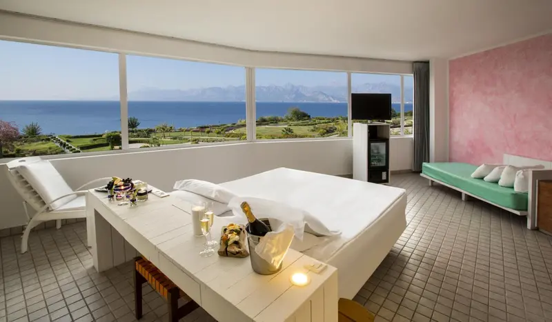 Chambre lumineuse avec vue sur la mer et un lit préparé pour une occasion spéciale.