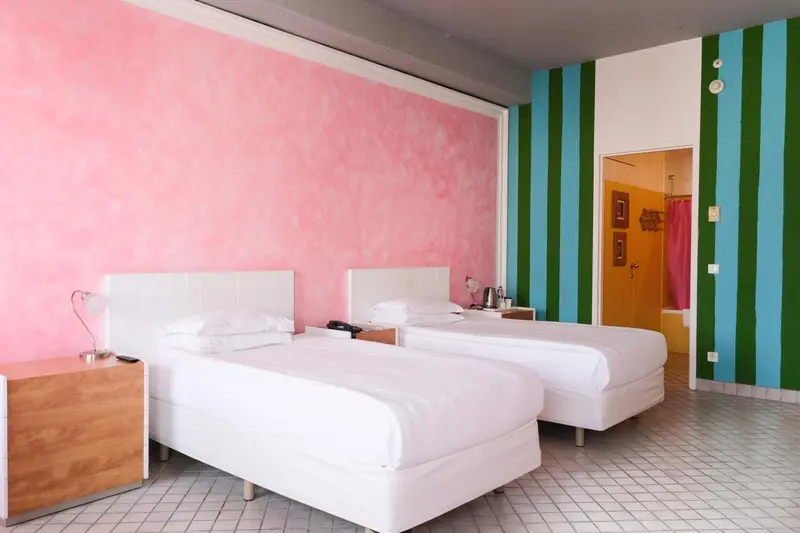 Chambre lumineuse avec deux lits simples et murs colorés.