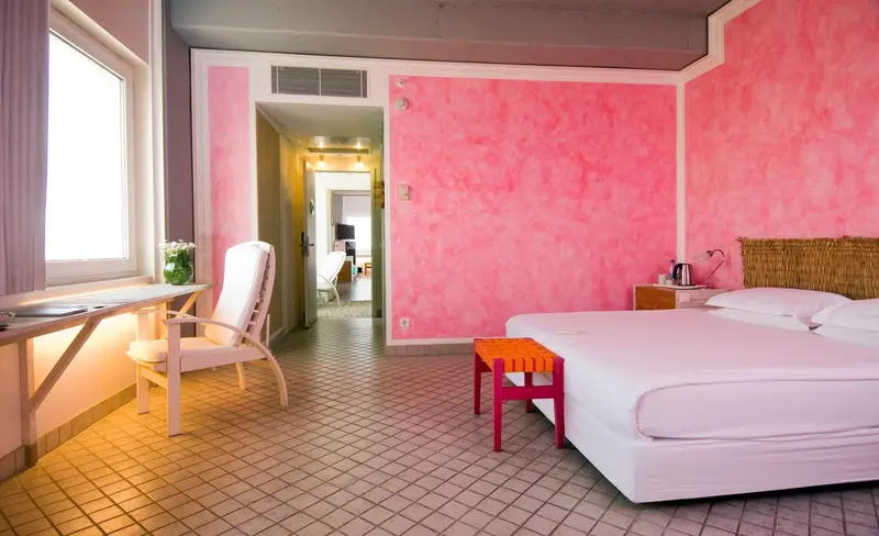 Chambre lumineuse aux murs roses et au mobilier moderne.