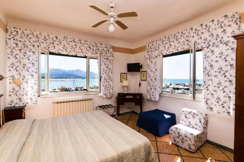 Une chambre lumineuse avec un lit et un bureau donnant sur une vue mer.