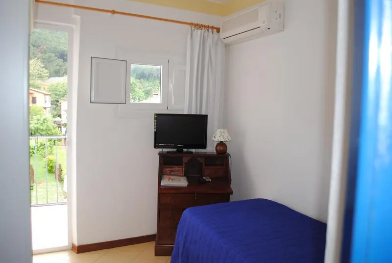 Une chambre lumineuse avec un lit bleu et un meuble télévision.