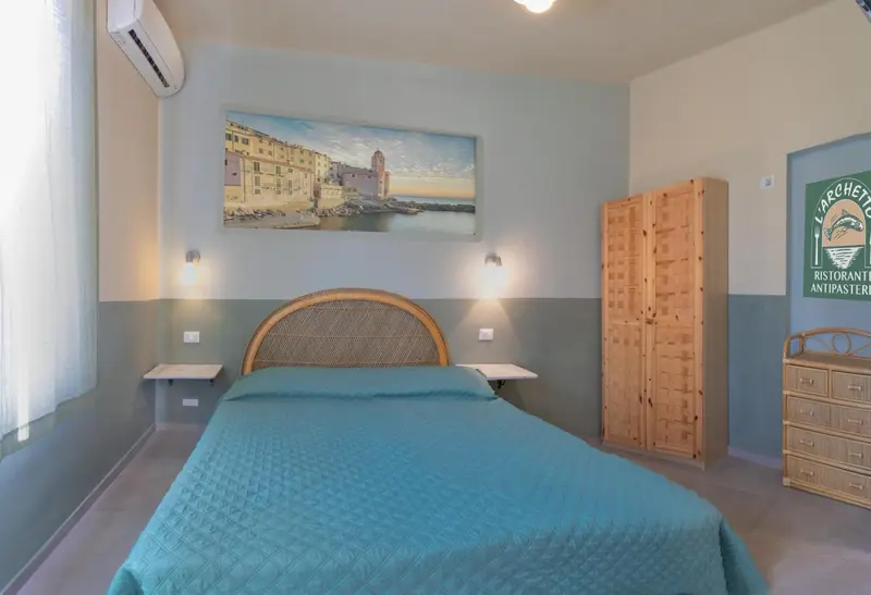 Chambre lumineuse avec un lit double et une décoration murale représentant un paysage marin.