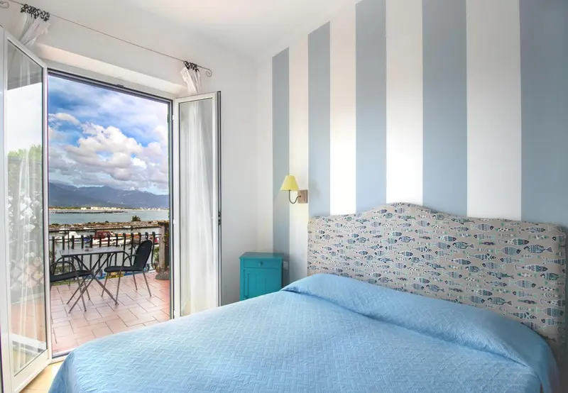 Une chambre lumineuse s'ouvre sur une terrasse avec vue sur la mer.