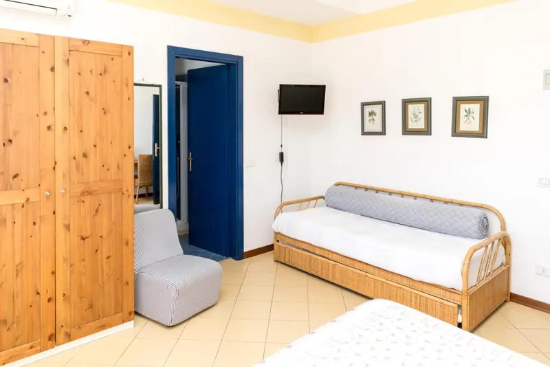 Une chambre lumineuse avec un canapé-lit et un placard en bois.