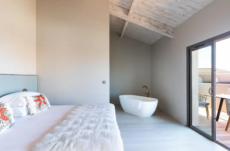 Une chambre lumineuse avec un grand lit et une baignoire sur pied.