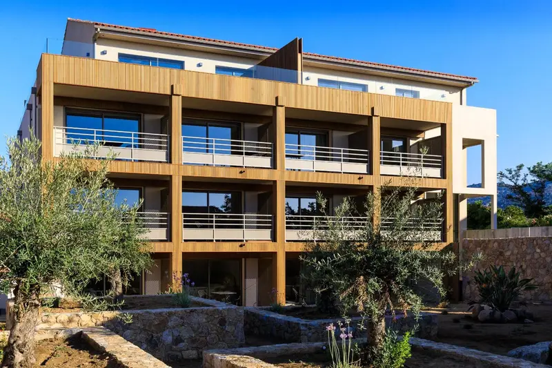 Bâtiment moderne à étages avec des balcons et une façade en bois.