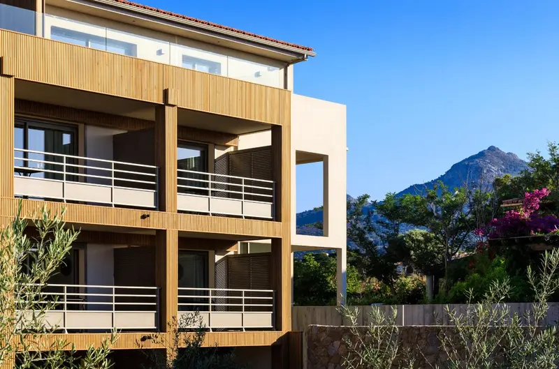 Façade d'un bâtiment moderne avec des balcons et une végétation luxuriante.