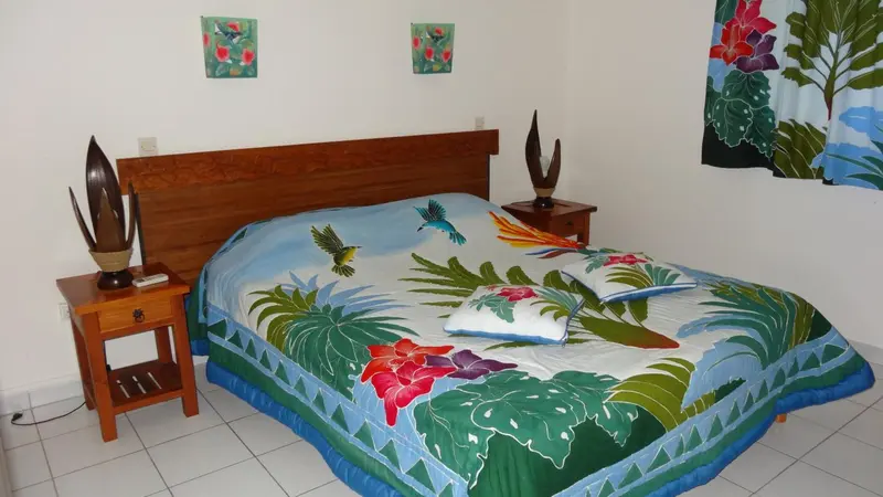 Une chambre avec un grand lit recouvert d'une courtepointe colorée.