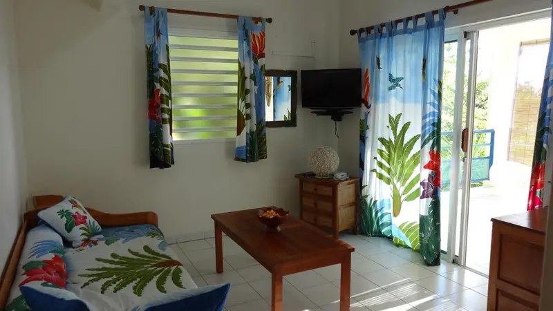 Une pièce lumineuse avec un canapé, une table basse et un téléviseur mural.