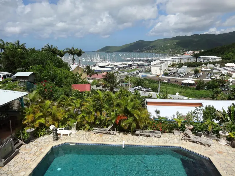 Vue panoramique sur une baie bordée de bâtiments et de végétation luxuriante.