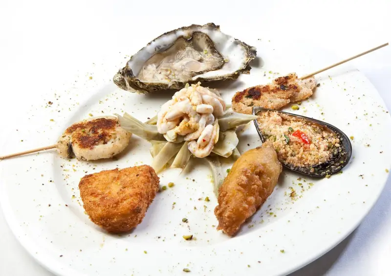Assortiment de fruits de mer et de poissons panés présentés sur une assiette blanche.