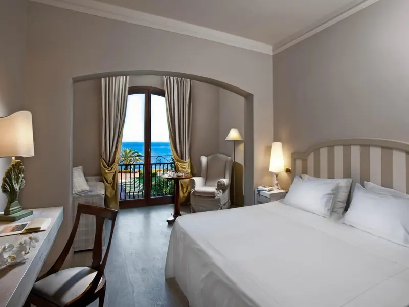 Une chambre lumineuse avec un lit double et un accès à un balcon offrant une vue sur la mer.