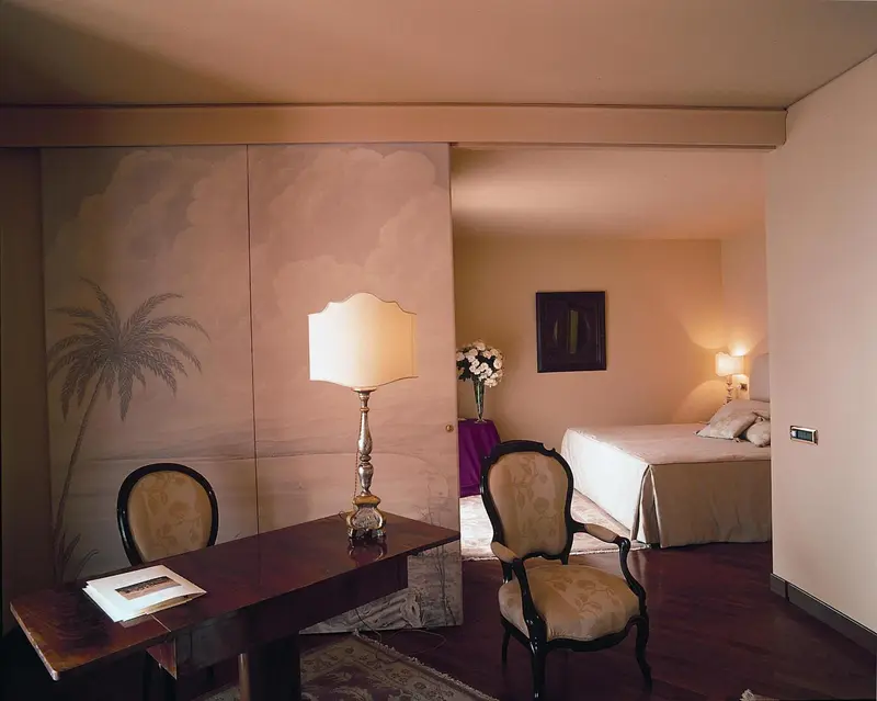 Une chambre à coucher lumineuse avec un bureau et des fauteuils.