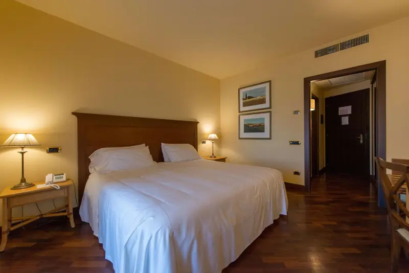 Une chambre lumineuse avec un grand lit recouvert d'une courtepointe blanche.