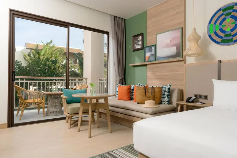 Une chambre lumineuse s'ouvre sur un balcon avec mobilier de jardin.