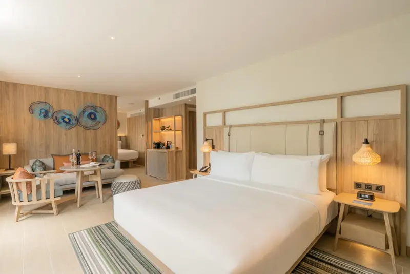 Une chambre lumineuse avec un lit et un coin salon.