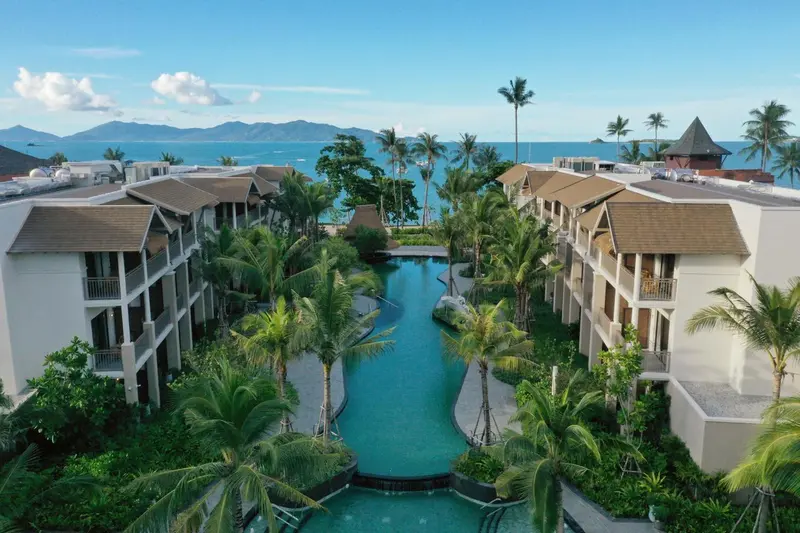 Vue aérienne d'un complexe hôtelier avec piscine sinueuse et végétation tropicale.