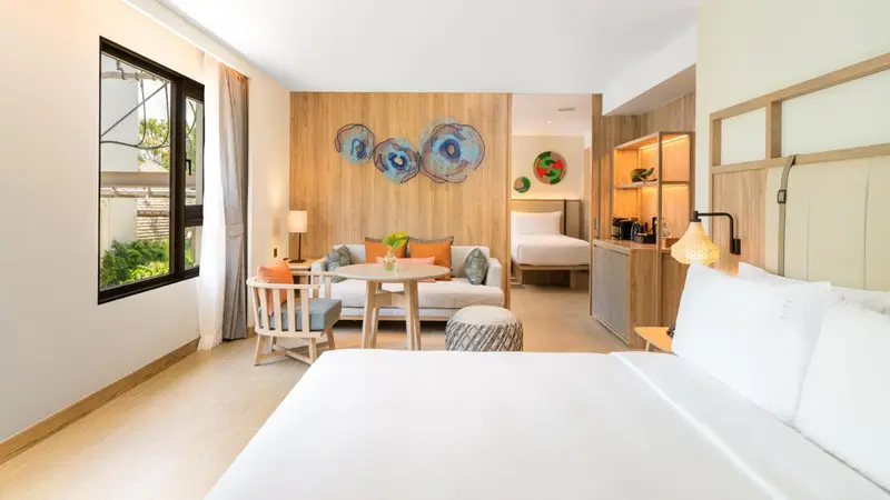 Une chambre lumineuse avec un coin salon et un lit double.
