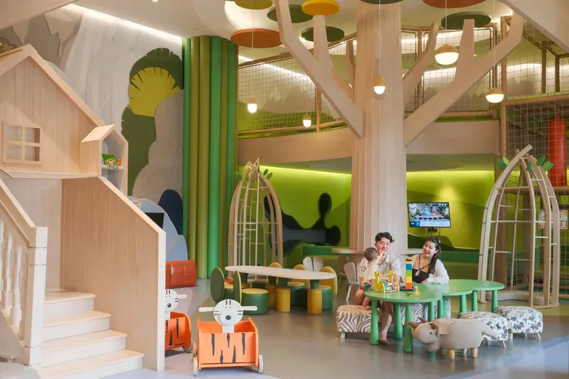 Espace de jeux intérieur avec structures en bois et mobilier coloré.