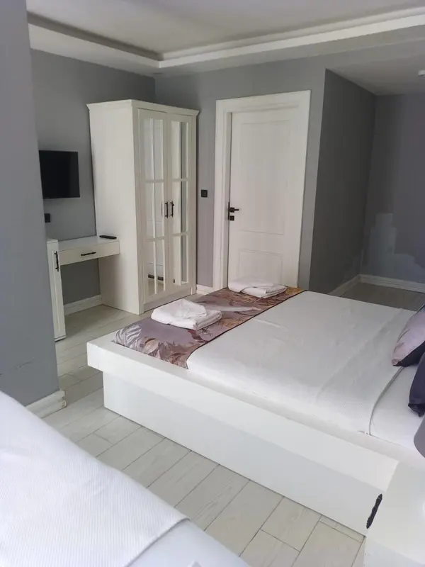 Une chambre lumineuse avec un lit fait et une armoire blanche.