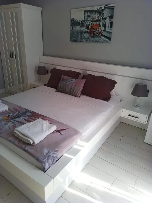 Une chambre lumineuse avec un grand lit recouvert d'une couette et de coussins.