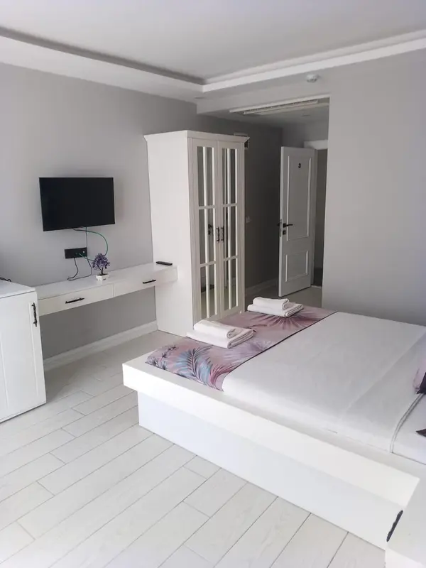 Une chambre lumineuse avec un lit et un meuble blanc.