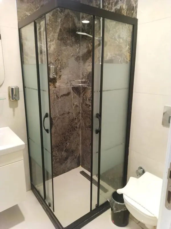 Une douche vitrée moderne dans une salle de bain claire.