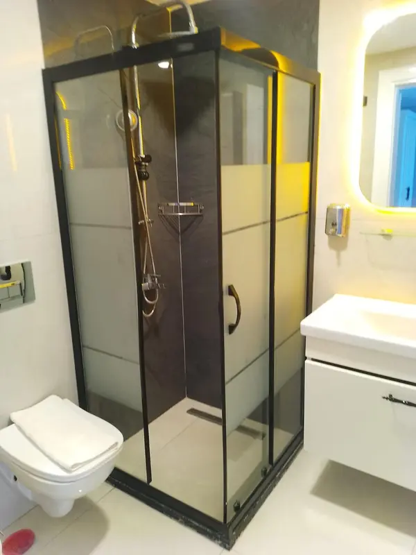 Une douche vitrée moderne dans une salle de bain claire.