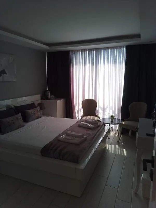 Une chambre lumineuse avec un grand lit et un coin salon près d'une fenêtre.