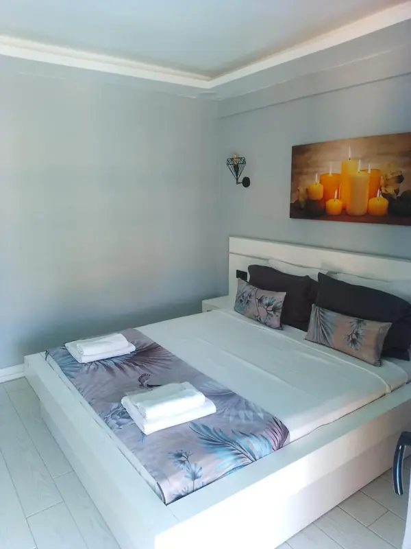 Une chambre lumineuse avec un grand lit recouvert de linge blanc et de coussins.