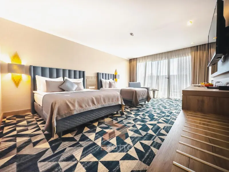 Une chambre d'hôtel moderne avec un grand lit et un tapis graphique.
