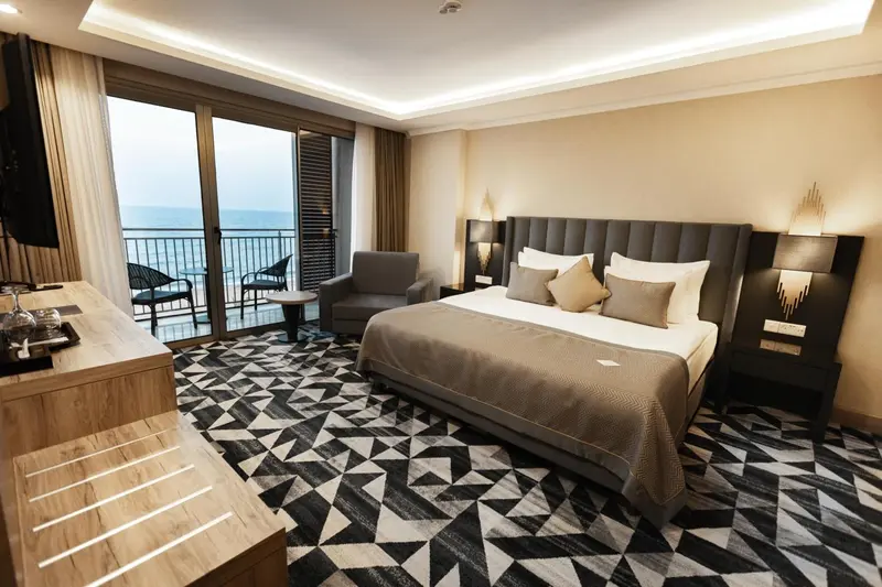 Une chambre avec un grand lit et un accès à un balcon donnant sur la mer.