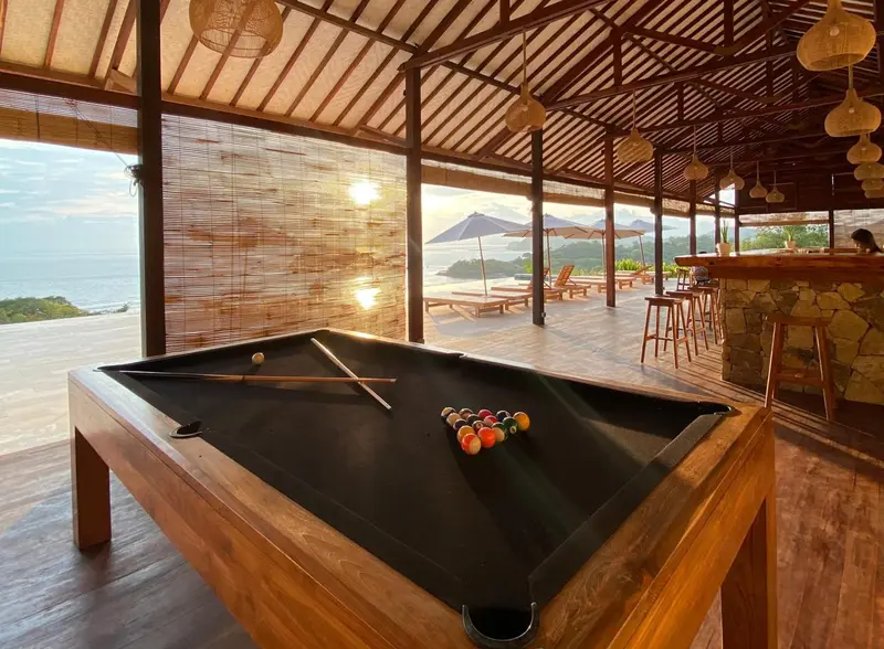 Une table de billard se trouve dans un espace ouvert avec vue sur la mer.