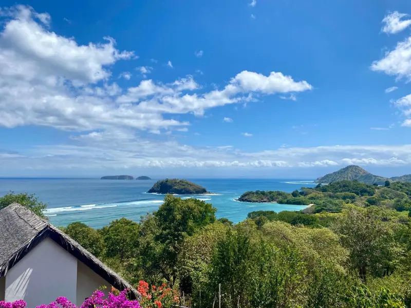 Vue panoramique sur une côte tropicale avec des îles verdoyantes et une mer turquoise.