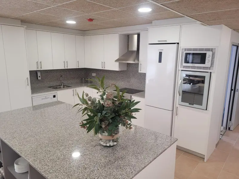 Une cuisine moderne et lumineuse avec un îlot central et des appareils électroménagers blancs.