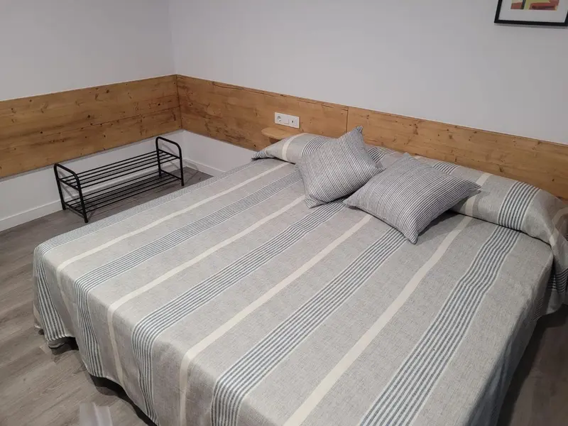 Une chambre avec un lit recouvert d'une couverture rayée et un mur en bois.