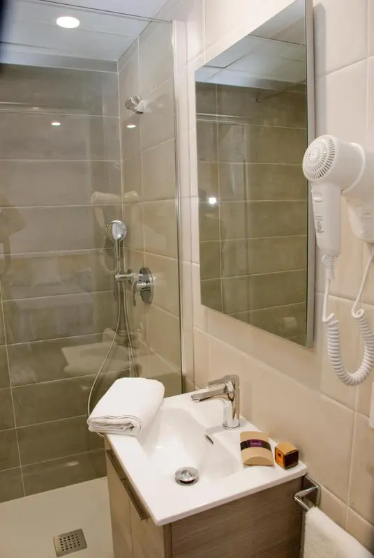 Une salle de bain moderne avec douche à l'italienne et sèche-cheveux mural.