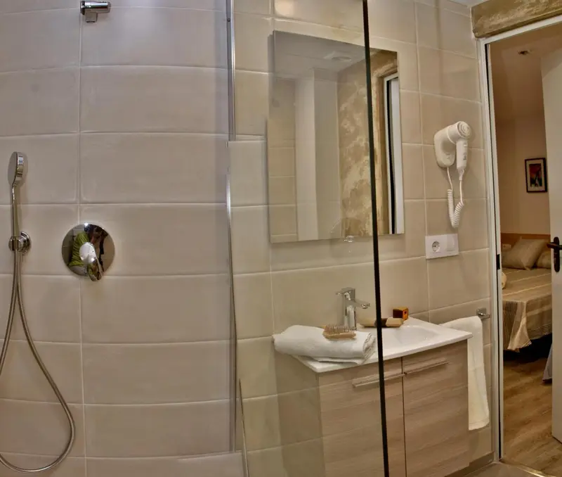 Une douche à l'italienne avec un lavabo et un sèche-cheveux mural.