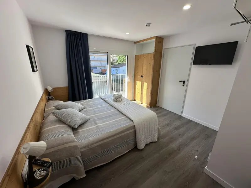 Une chambre lumineuse avec un grand lit et un accès à une terrasse.