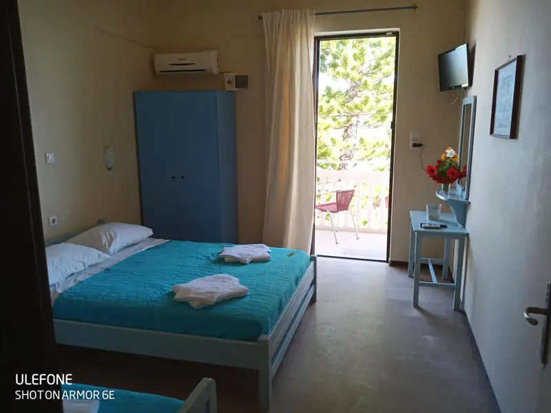 Une chambre lumineuse avec un lit fait et une terrasse accessible par une porte-fenêtre.