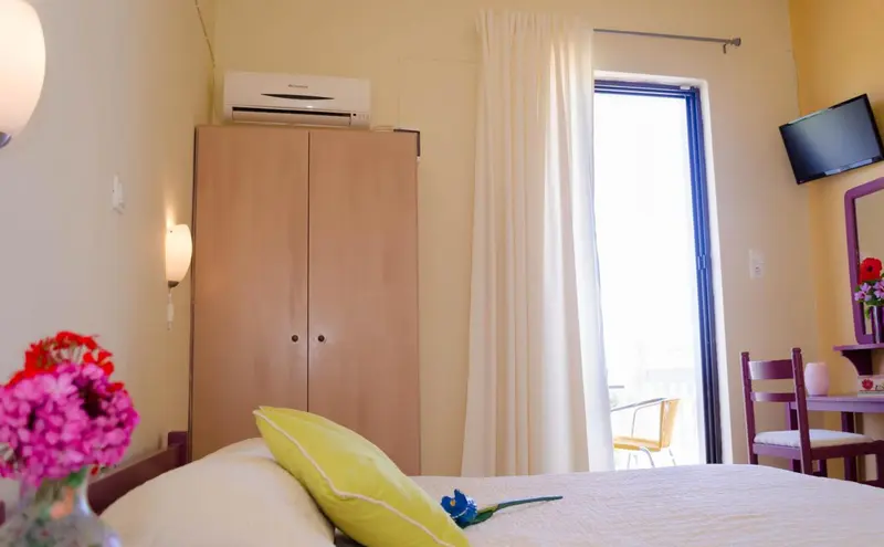 Une chambre lumineuse avec un lit, une armoire et une table.